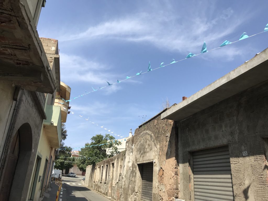 Blaue Wimpel auf Sardinien zwischen Häusern gespannt